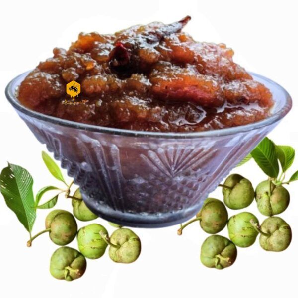 Glass bowl filled with sweet Chalta Chutney topped with red chili alongside fresh raw elephant apples on white background